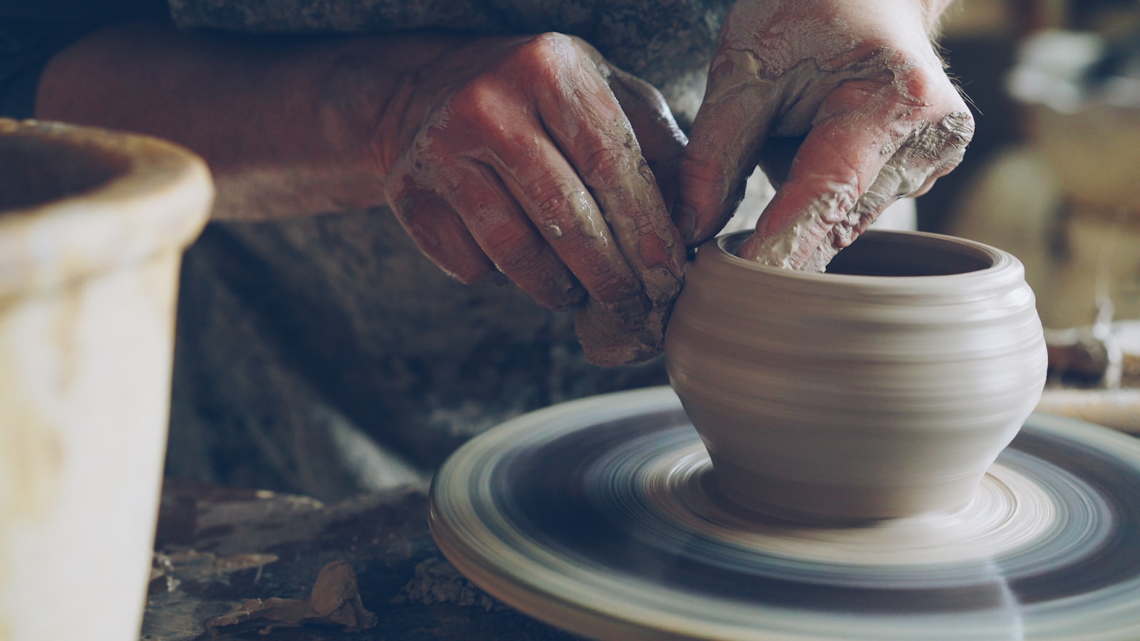Hands shaping wet clay on a pottery wheel