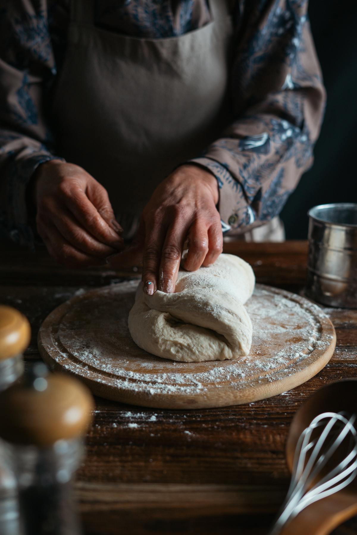 The bone linen apron worn at a workbench, kneading dough