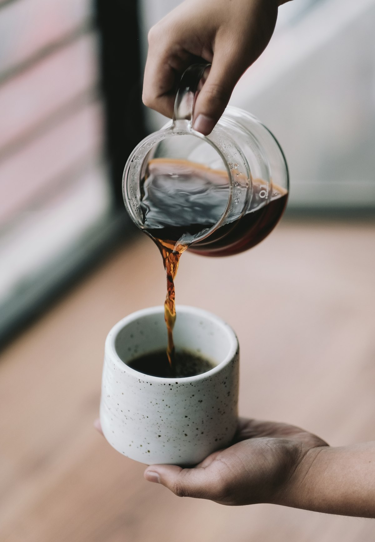 Coffee being poured into a speckled stoneware mug